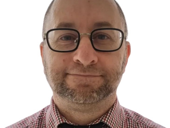 Tome Velkovski, smiles at the camera. He wears a red and white checkered shirt paired with a black tie against a plain white background. From Yes property agents website